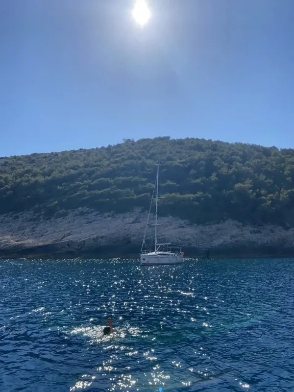 Jedrilica plovi pored ostrva sa sunčevom svetlošću