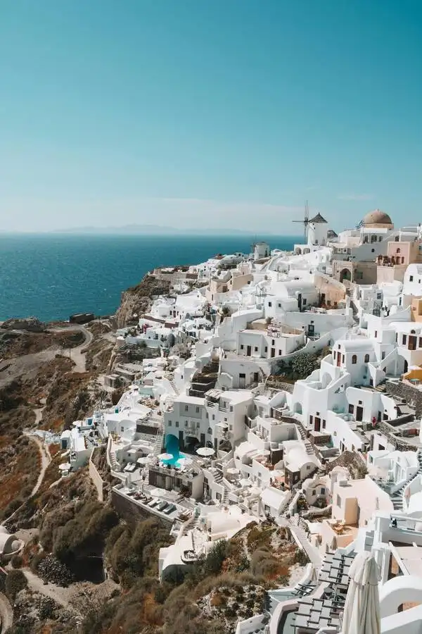 Santorini kaldera sa belim selom Oia na vrhu litice i jedrilicama na moru